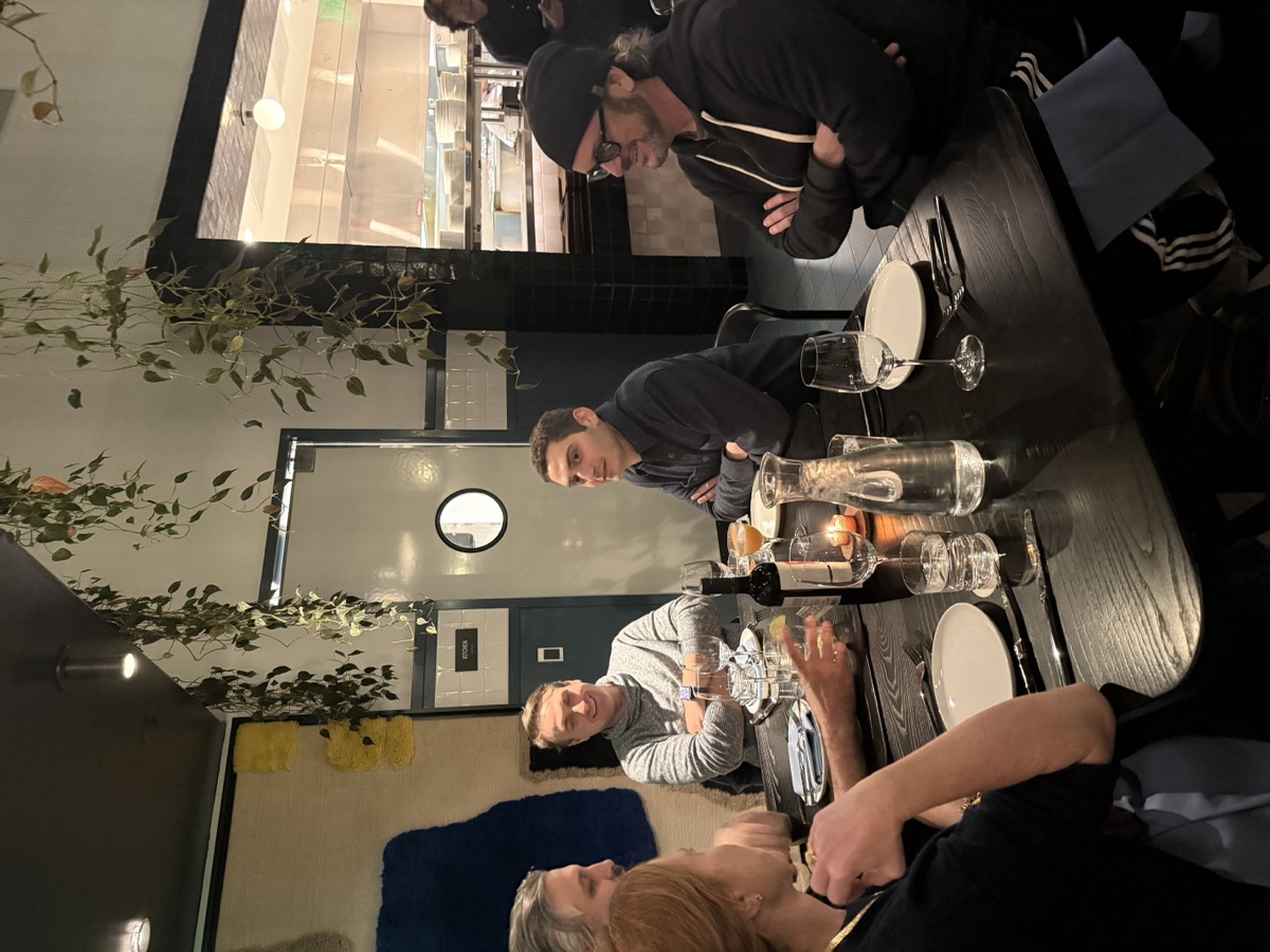 A dinner conversation, five people leaning in around a candlelit table